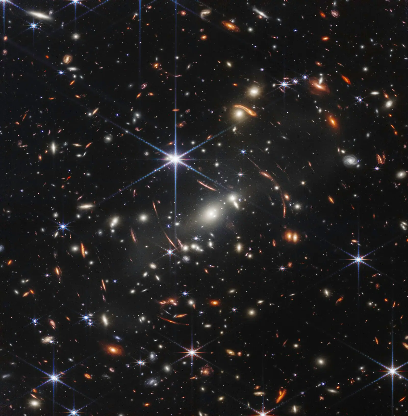 Photographie spatiale : sur fond noir, des milliers de taches lumineuses, blanches et orangées, certaines étirées en arcs.