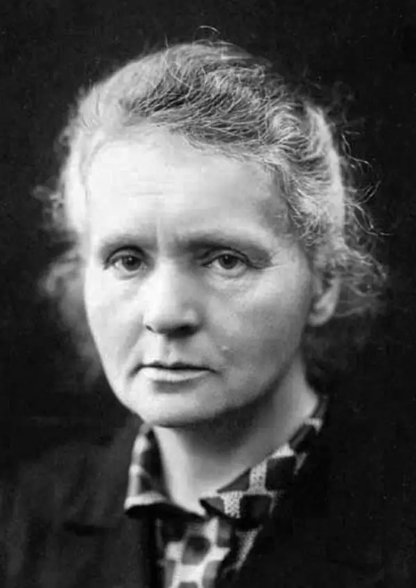 Photographie en noir et blanc : Marie Curie, cheveux gris relevés, regarde l'objectif avec gravité.