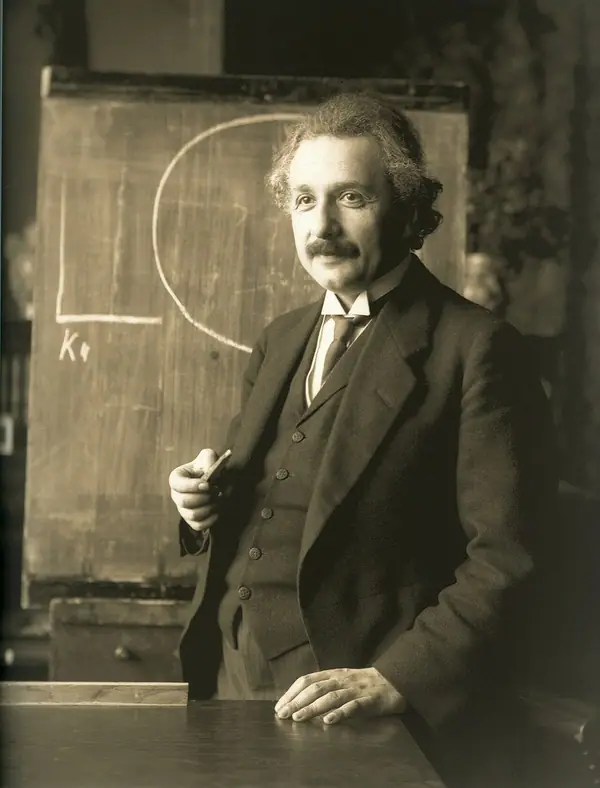 Photographie en noir et blanc d'un homme aux cheveux en bataille et à la moustache, en costume.