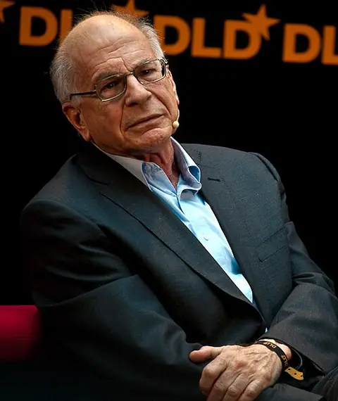 Photographie : Daniel Kahneman, cheveux blancs et lunettes, assis en veste sombre sur une scène.
