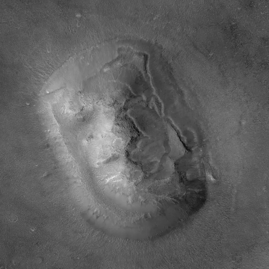 Photographie détaillée en noir et blanc : une colline érodée aux flancs irréguliers, sans rien d'un visage.