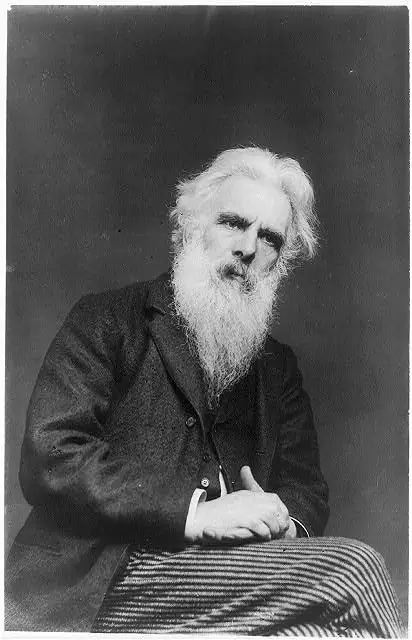 Photographie : Eadweard Muybridge âgé, longue barbe blanche, assis les mains jointes.