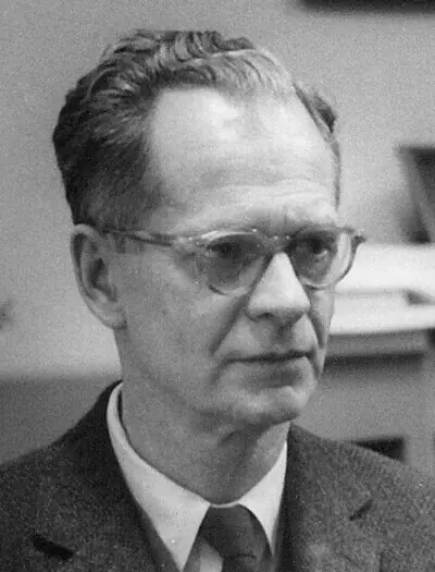 Photographie en noir et blanc : B. F. Skinner, en costume et lunettes, regarde vers la gauche.